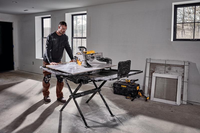 High Capacity Wet Tile Saw with stand being used by a construction worker to cut a tile